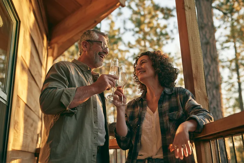American couple toasting sparkling water on a porch celebrating a milestone trip